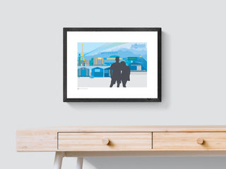 A bespoke print with a skyline of landmarks and a silhouette of a couple, above a wooden console table.