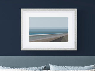 A framed and mounted art print featuring a coastal scene with blue and grey tones, displayed above a bed in a bedroom setting.