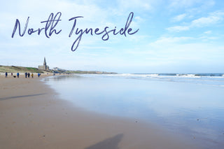 Wide sandy Tynemouth beach with gentle waves along the shore.