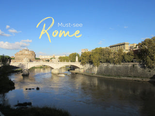 blue-sky day in Rome, looking down the river at a bridge and castle.