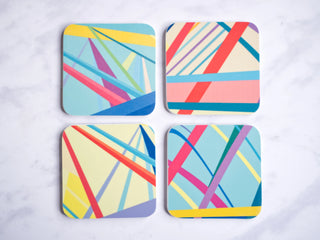 Four multicoloured drinks coasters with an abstract geometric design.