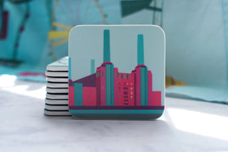Battersea Power Station coaster leaning against a stack of coasters in front of a blue tea towel.