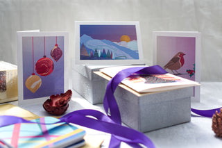 Display of Christmas cards sitting on top of sparkly silver gift boxes.