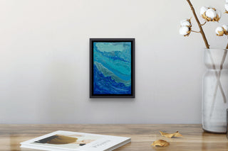 Framed blue fluid painting vitality by south island art above a wooden table with magazine.