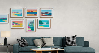 Modern living room with a blue sofa, coffee table, and colourful beach-themed wall art.