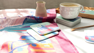 Colourful coasters illustrated with London landmarks sit on a bright tea towel of the London skyline